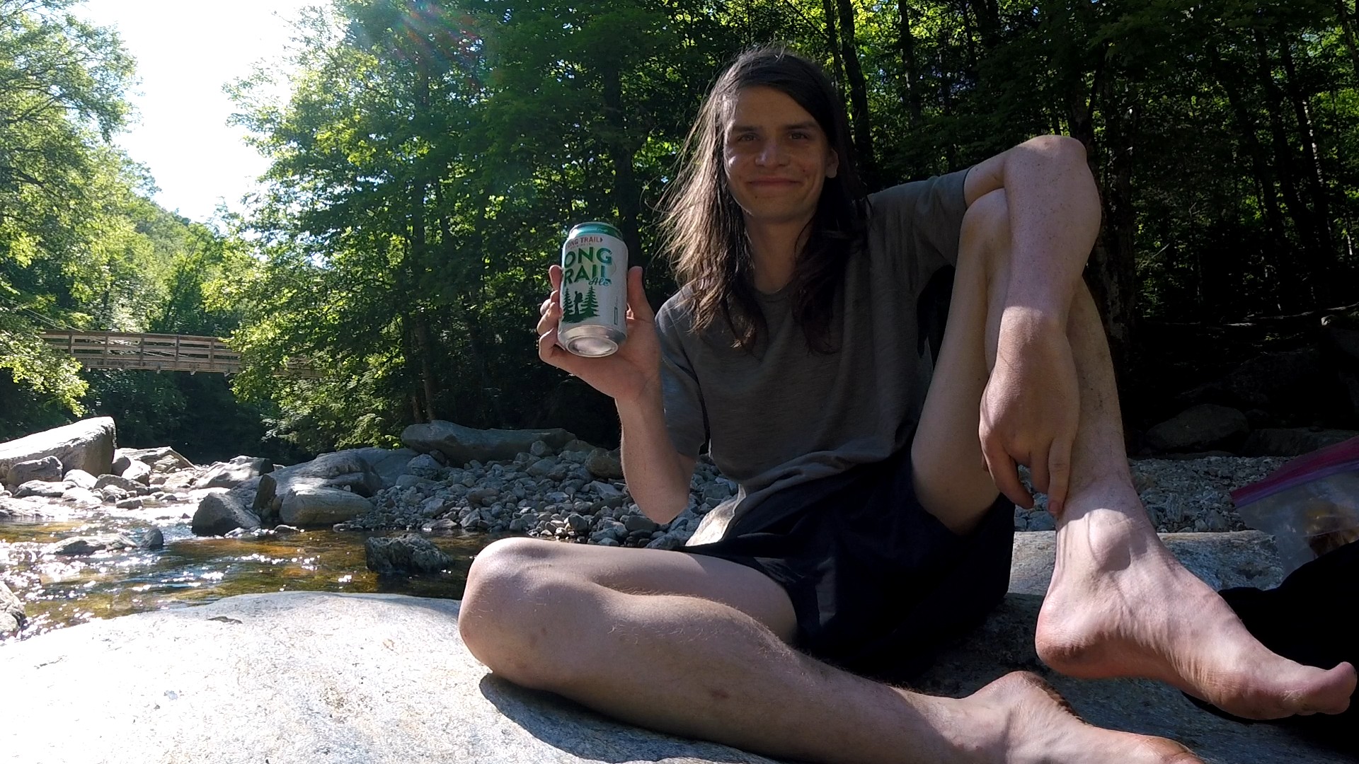 Sitting on a rock holding a can of Long Trail Ale