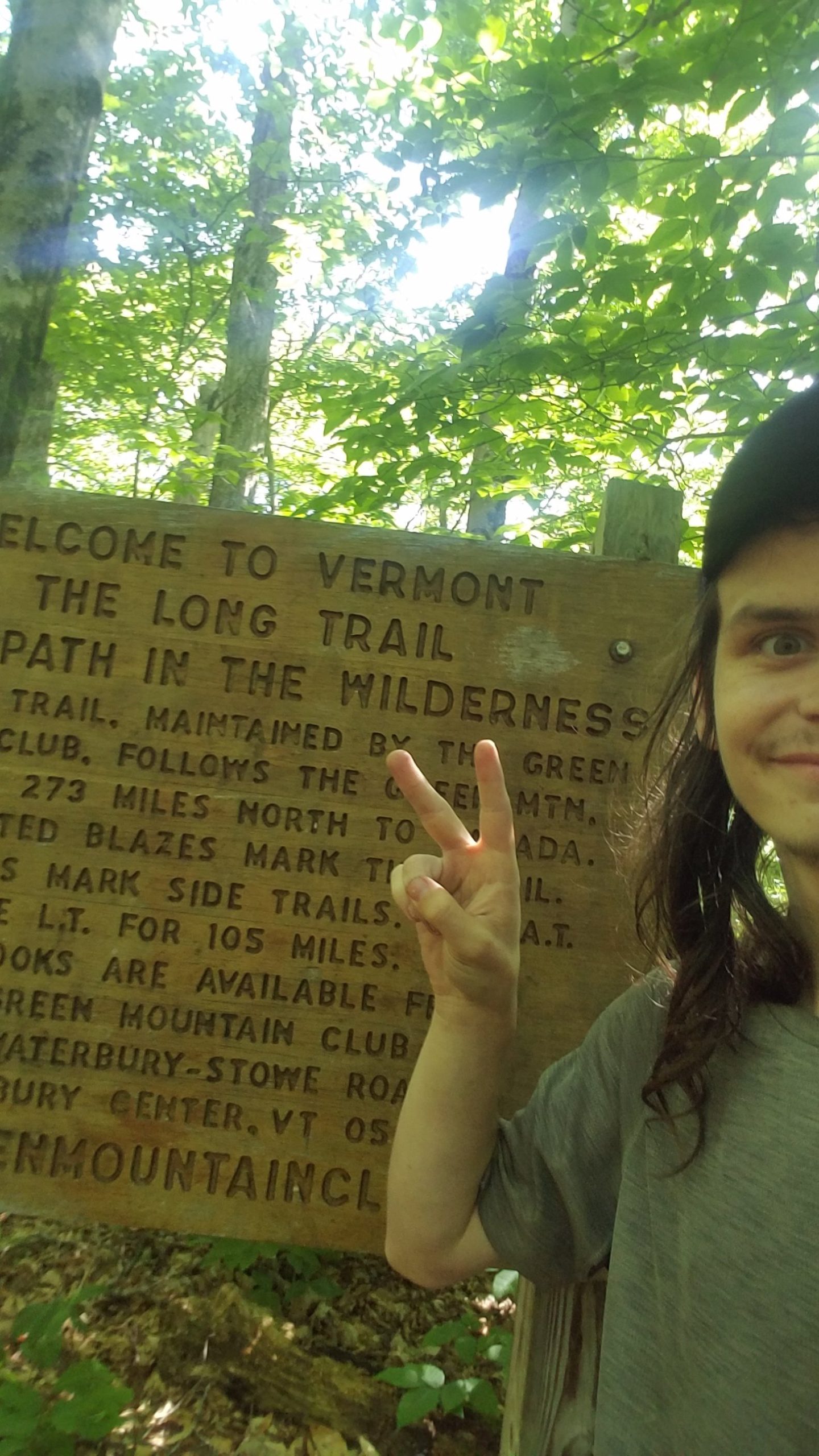 I stand at the Vermont border with a sign indicating the start of the Long Trail ehind me