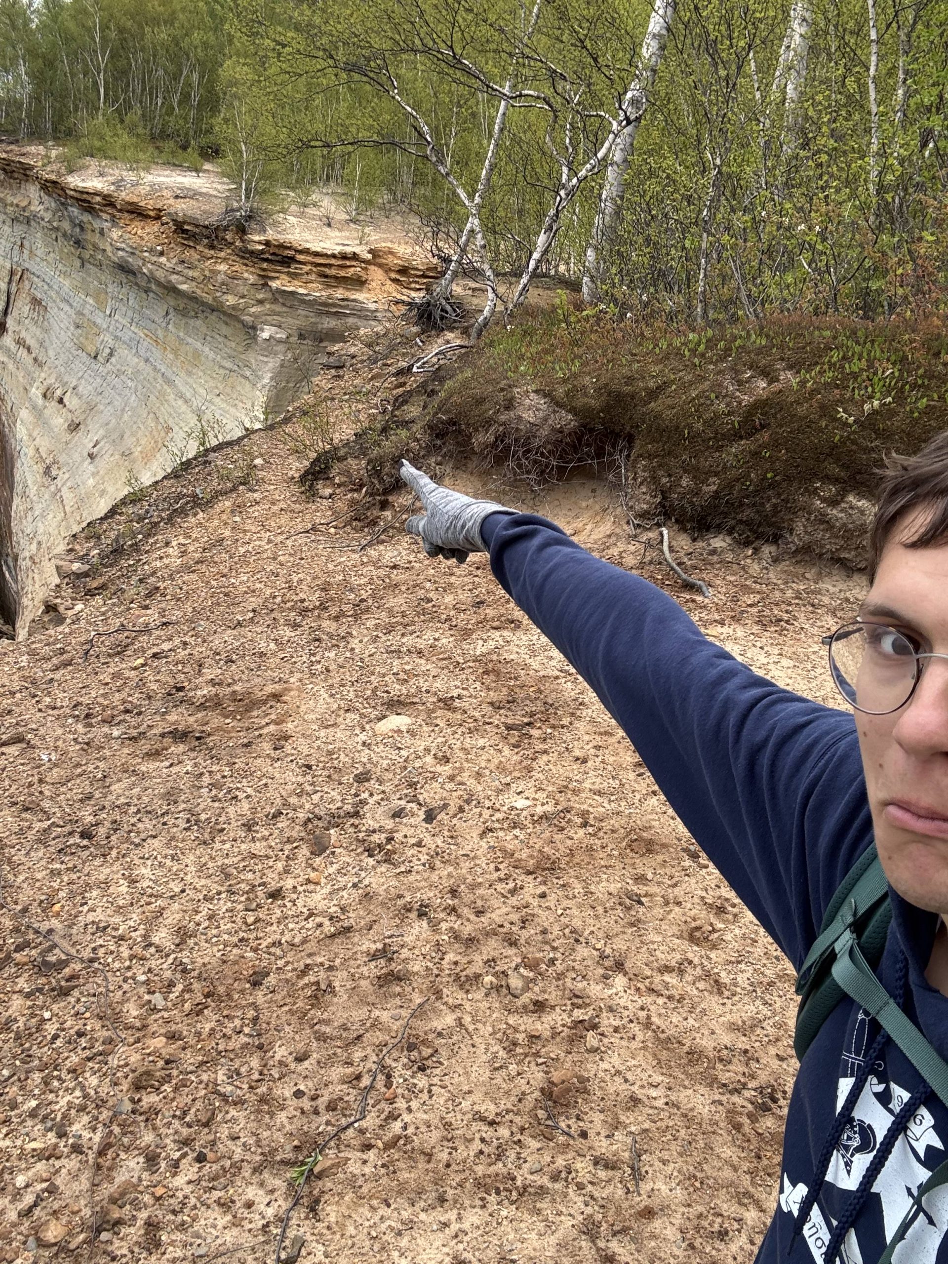 Writer pointing to a patch of exposed cliff.