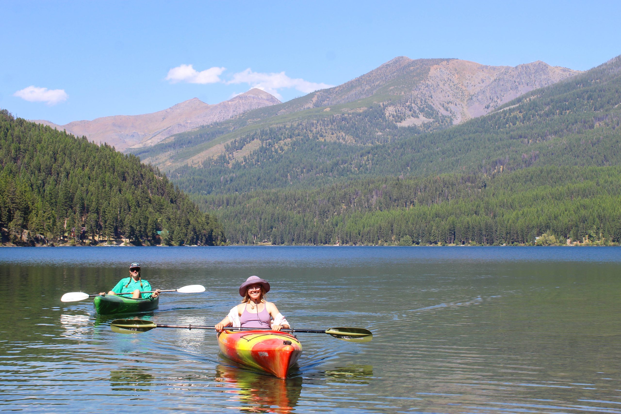 glasses vs. contacts for thru-hiking: kayakers on a mountain lake wearing hats and sunglasses