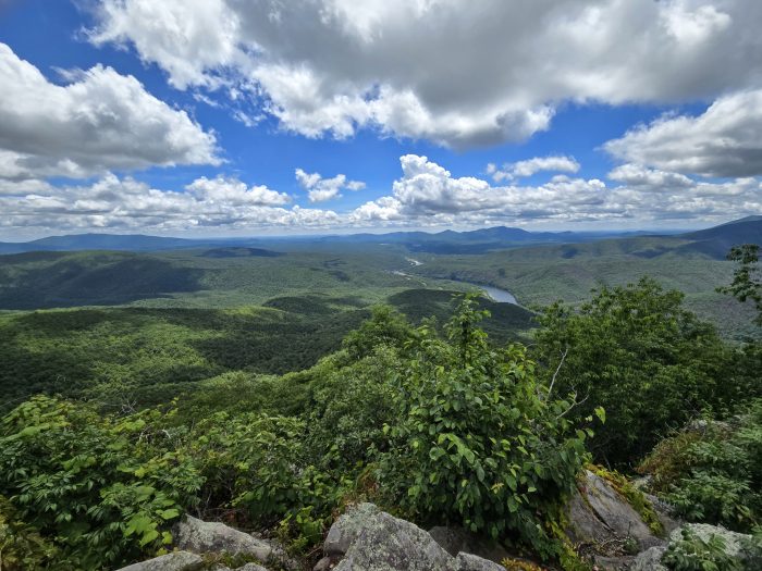 Mountain panorama with green mountains, blue sky and white clouds.