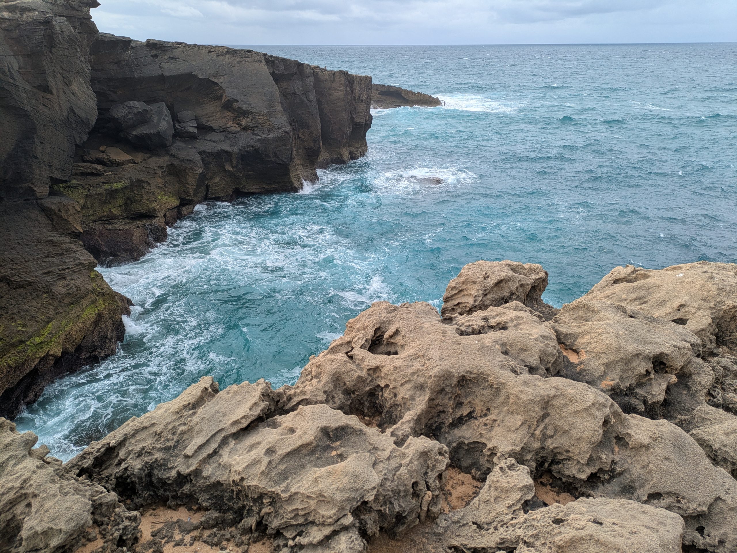 The irregular black cliffs with wavy rock formations carved in waves along the Portuguese coast, with a view to the Atlantic Ocean.
