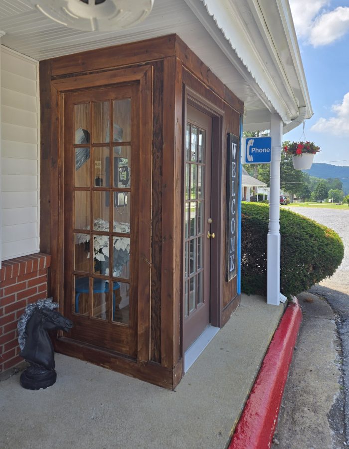 An old oak telephone booth with a salary phone inside