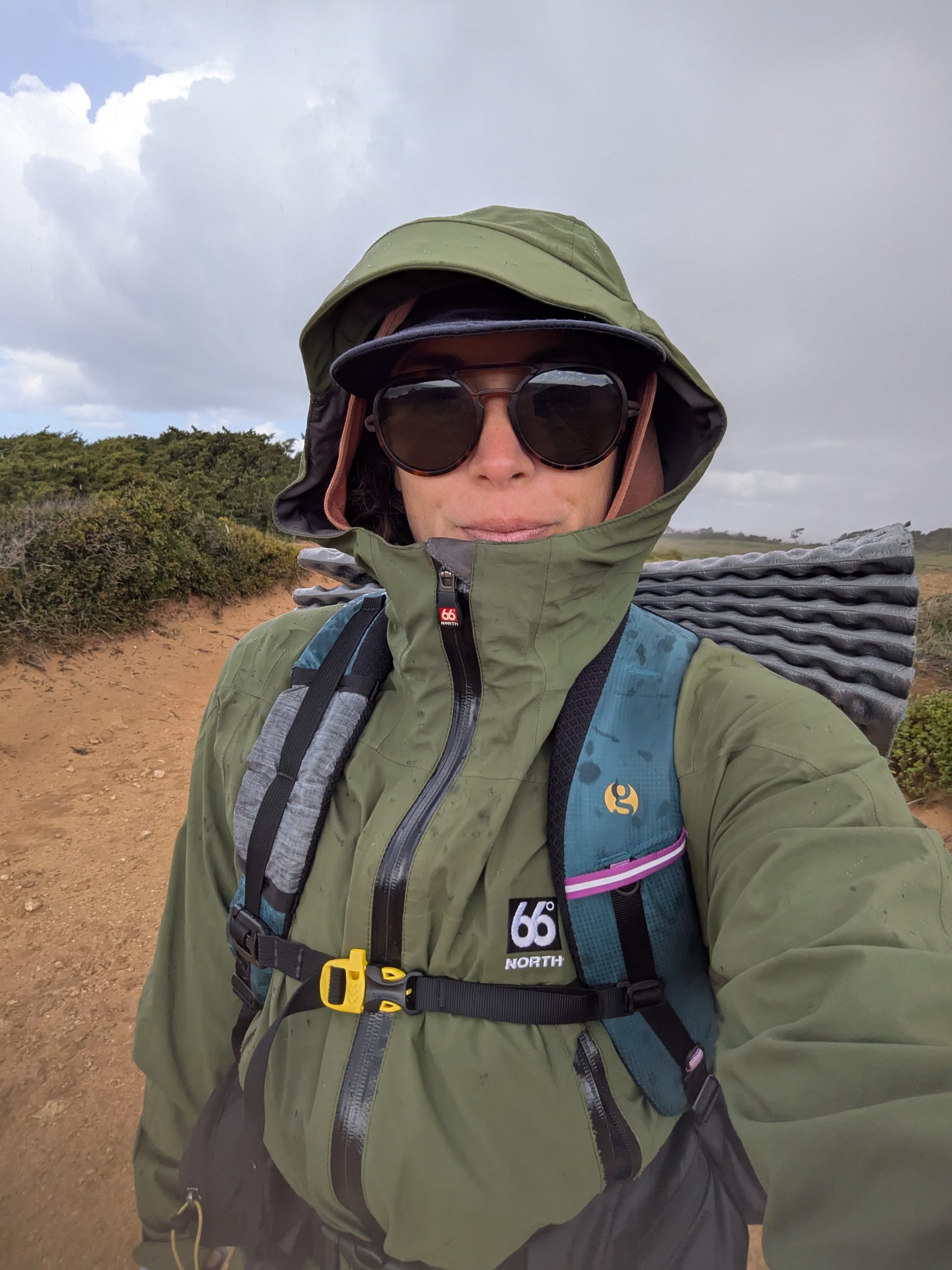 Caminante con chaquetas de lluvia en pescadores, navegue por los cambios climáticos y el cielo turbio y la casa costera en Portugal.