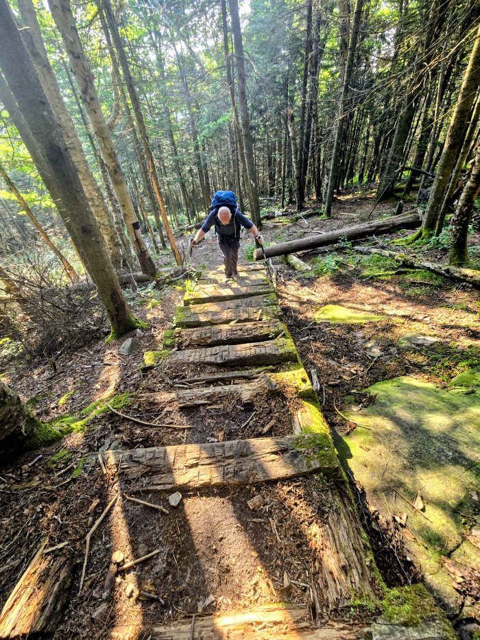 Male hiker ascending a long game of steep stairs on the path