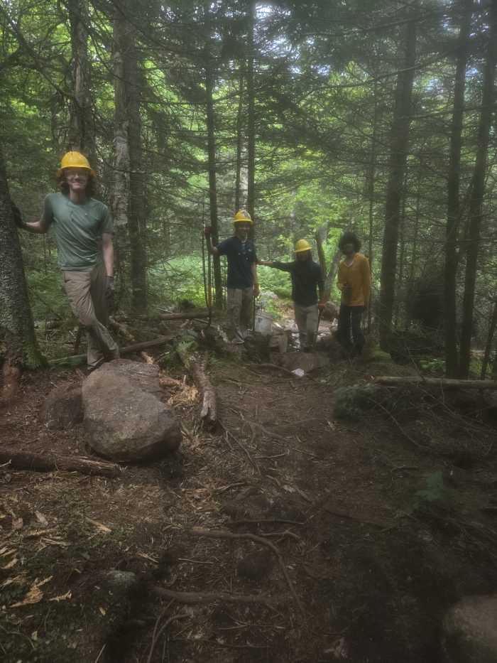 Cuatro hombres trabajan en un sombrero duro para construir una salida de la roca original.