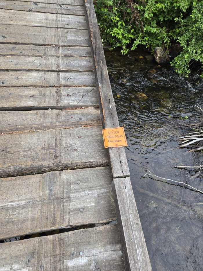 Water medimina on water with orange sign that says the boundary of the Baxter State Park.