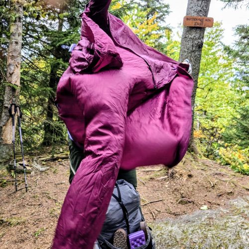 Person trying to put on a jacket in the wind while the jacket is billowing in the wind