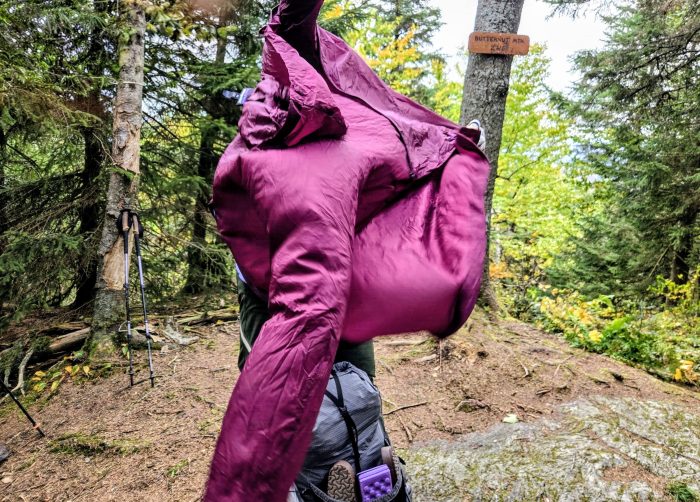 Person trying to put on a jacket in the wind while the jacket is billowing in the wind