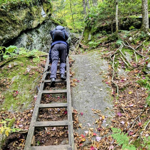Backpacker comong down a cliff ladder