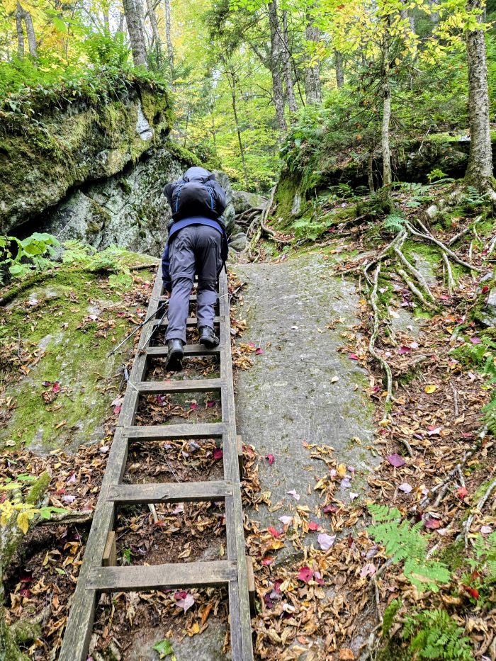 Backpacker comong down a cliff ladder