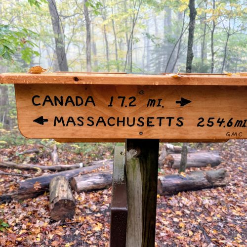 Wooden sign saying Canada, 17 and one half miles